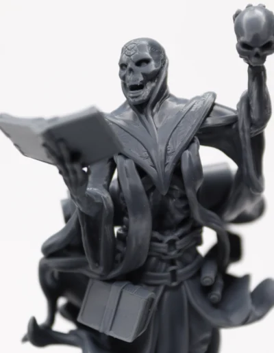 SLA 3D Print - a grey statue of a skeleton holding a book